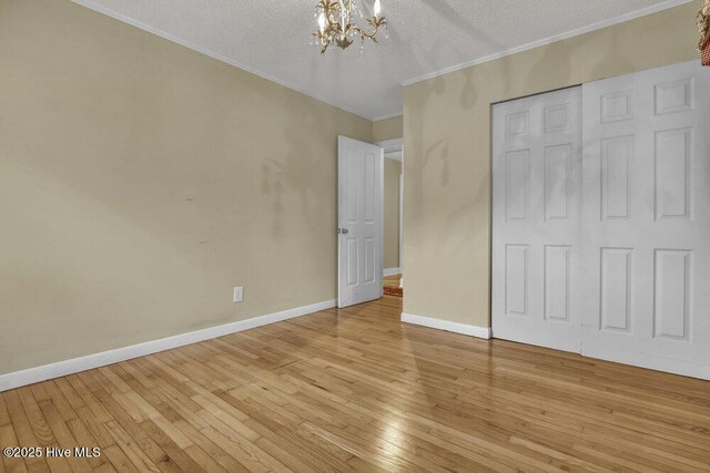408 N 25th St, Wilmington, NC 28405 - unfurnished bedroom with a chandelier, light wood-style floors, ornamental molding, a textured ceiling, and baseboards