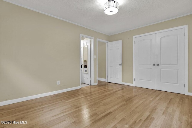 408 N 25th St, Wilmington, NC 28405 - unfurnished bedroom featuring a textured ceiling, light wood-style flooring, crown molding, baseboards, and a closet