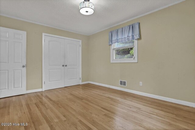 408 N 25th St, Wilmington, NC 28405 - unfurnished bedroom featuring a closet, light wood finished floors, crown molding, baseboards, and a textured ceiling