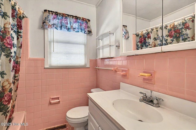 5685 Watts Rd SW, Ocean Isle Beach, NC 28469 - bathroom featuring tile walls, ornamental molding, vanity, toilet, and wainscoting