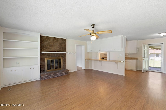 263 La Grange Rd, La Grange, NC 28551 - unfurnished living room featuring a textured ceiling, light wood finished floors, ceiling fan, and a brick fireplace