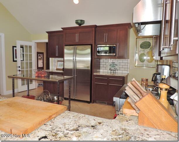 110 E Blalock Rd, Lucama, NC 27851 - kitchen featuring stainless steel appliances, tasteful backsplash, light tile patterned floors, vaulted ceiling, and light stone countertops
