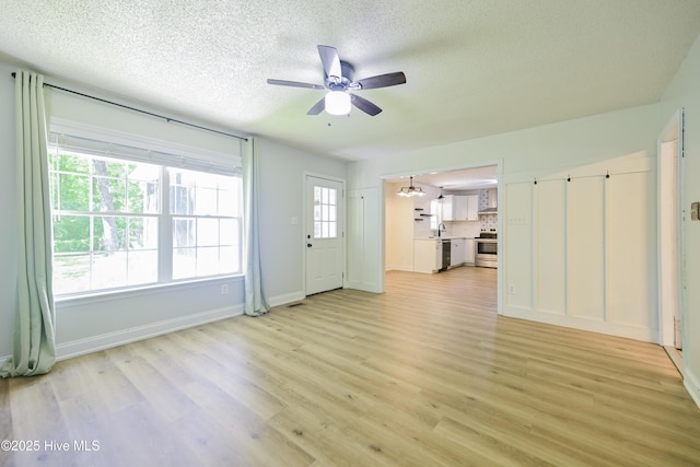 159 Dockside Dr, Jacksonville, NC 28546 - unfurnished living room with ceiling fan, a textured ceiling, light wood-type flooring, baseboards, and a sink