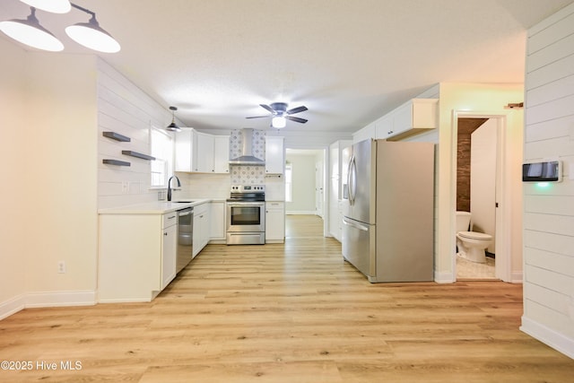 159 Dockside Dr, Jacksonville, NC 28546 - kitchen featuring stainless steel appliances, wall chimney exhaust hood, a ceiling fan, and light wood-style flooring