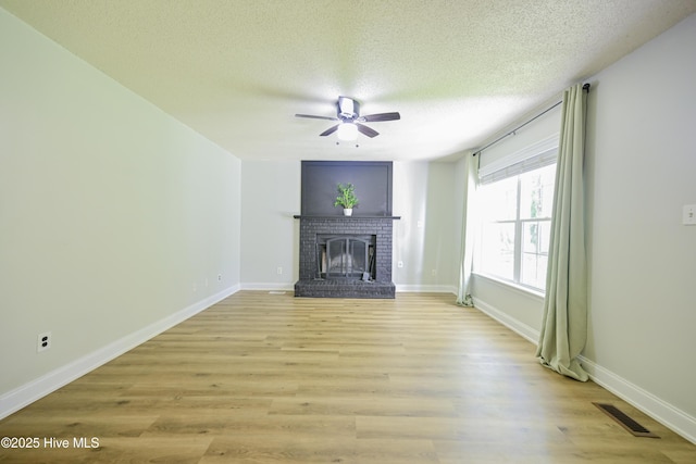 159 Dockside Dr, Jacksonville, NC 28546 - unfurnished living room with a ceiling fan, a fireplace, a textured ceiling, light wood-style flooring, and baseboards