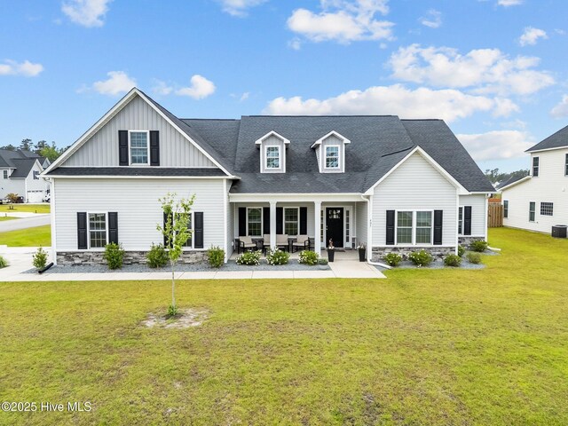 405 N Ardsley Ln, Rocky Point, NC 28457 - view of front of home featuring stone siding, a front yard, board and batten siding, central AC, and roof with shingles