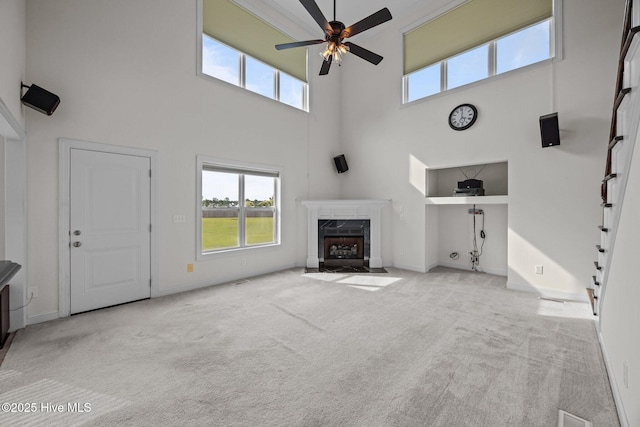 3107 Indian Wells Pl, Greenville, NC 27858 - unfurnished living room featuring a towering ceiling, a ceiling fan, carpet flooring, a high end fireplace, and baseboards