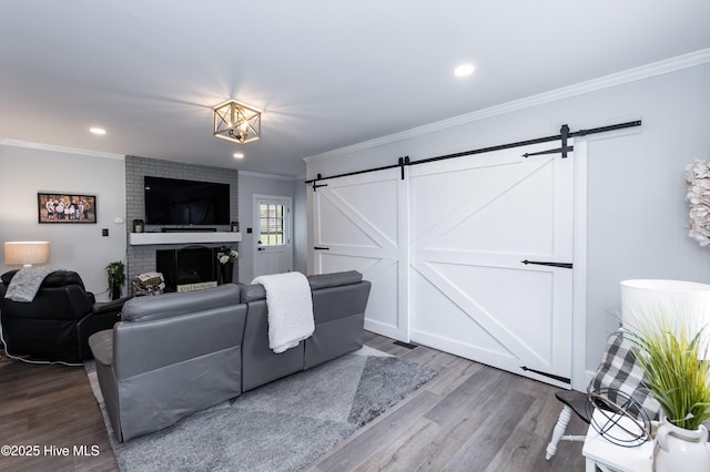 103 Midway Ln, Roanoke Rapids, NC 27870 - living room featuring a barn door, wood finished floors, ornamental molding, a brick fireplace, and recessed lighting