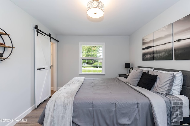 103 Midway Ln, Roanoke Rapids, NC 27870 - bedroom featuring a barn door, wood finished floors, and baseboards