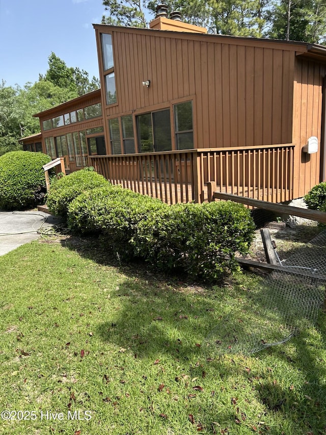 106 Eagle Ln, Hampstead, NC 28443 - view of side of property featuring a chimney, a lawn, board and batten siding, and a deck