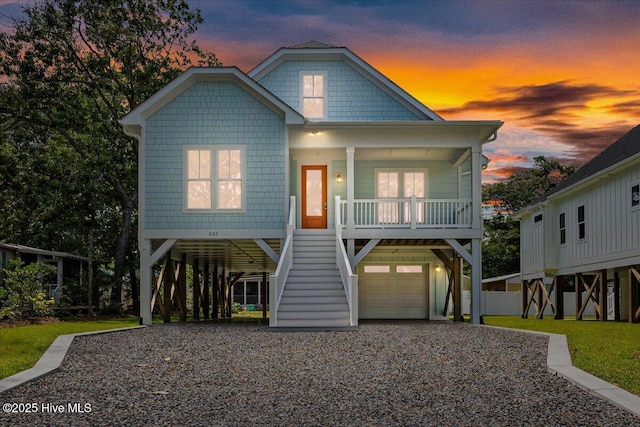243 NE 70th St, Oak Island, NC 28465 - coastal inspired home featuring covered porch, stairway, gravel driveway, a carport, and an attached garage