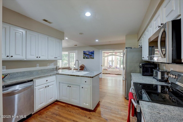 547 Deer Run Rd, New Bern, NC 28562 - kitchen with appliances with stainless steel finishes, a sink, white cabinetry, light wood finished floors, and a peninsula