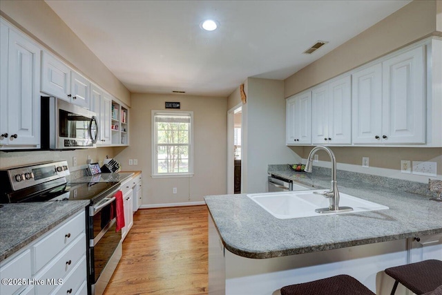 547 Deer Run Rd, New Bern, NC 28562 - kitchen with appliances with stainless steel finishes, a sink, white cabinetry, a breakfast bar area, and light wood-style flooring