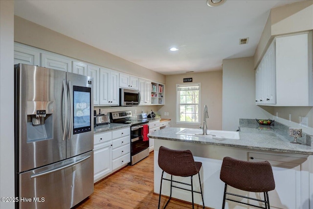 547 Deer Run Rd, New Bern, NC 28562 - kitchen with stainless steel appliances, a peninsula, a sink, white cabinets, and recessed lighting