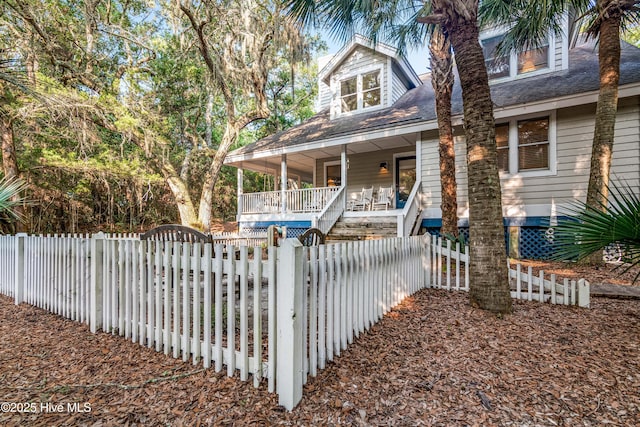 20 Fort Holmes Trl, Bald Head Island, NC 28461 - view of front facade featuring a porch, a shingled roof, a fenced front yard, and a gate