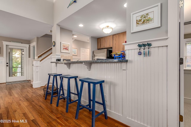 20 Fort Holmes Trl, Bald Head Island, NC 28461 - kitchen with refrigerator, a wainscoted wall, wood finished floors, a kitchen bar, and a decorative wall