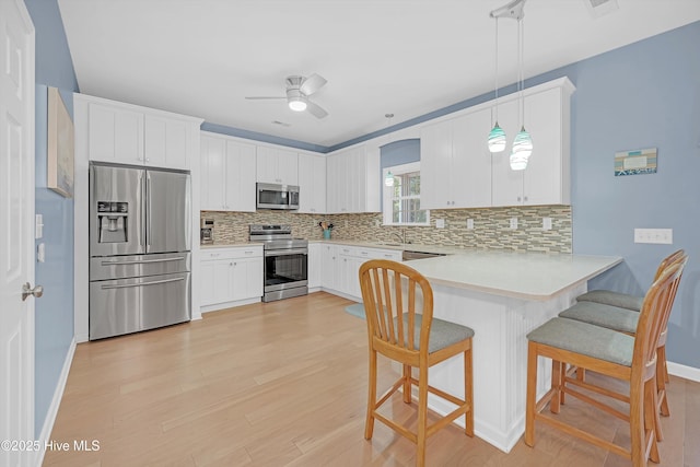 409 Womble St, Oak Island, NC 28465 - kitchen featuring appliances with stainless steel finishes, a sink, backsplash, a peninsula, and ceiling fan