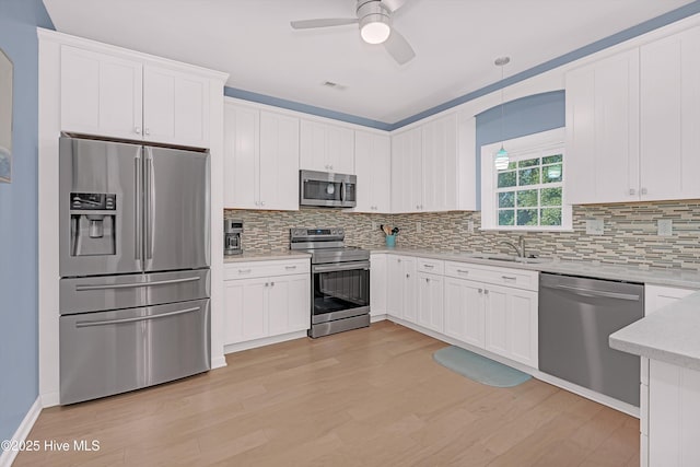 409 Womble St, Oak Island, NC 28465 - kitchen featuring stainless steel appliances, a sink, a ceiling fan, light wood finished floors, and backsplash