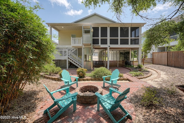 409 Womble St, Oak Island, NC 28465 - back of property featuring an outdoor fire pit, stairs, a sunroom, and a patio area