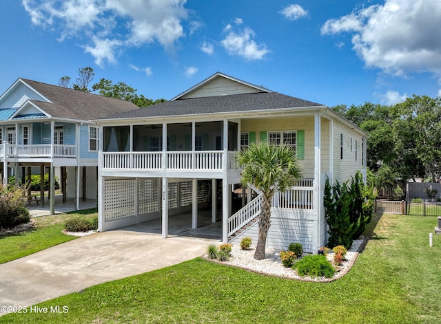 409 Womble St, Oak Island, NC 28465 - back of house with concrete driveway, a sunroom, a shingled roof, stairway, and a carport