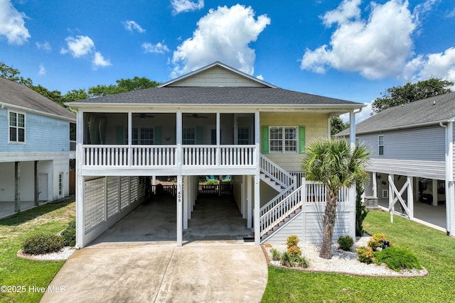 409 Womble St, Oak Island, NC 28465 - raised beach house featuring ceiling fan, concrete driveway, a sunroom, and a shingled roof