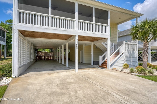 409 Womble St, Oak Island, NC 28465 - view of front facade with concrete driveway, a carport, a sunroom, and stairway
