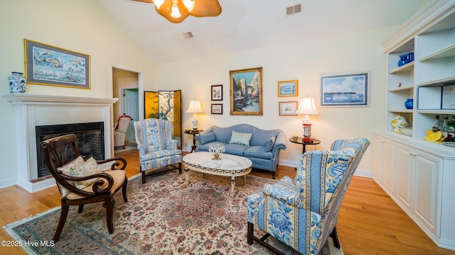 777 Marsh Rose Path NW, Calabash, NC 28467 - living area featuring light wood-style flooring, a ceiling fan, vaulted ceiling, a glass covered fireplace, and baseboards