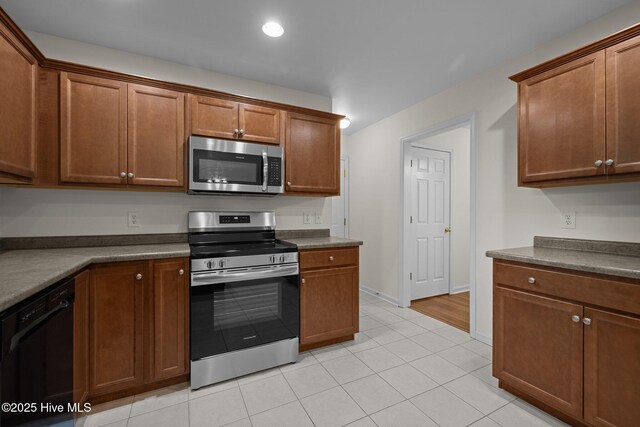 123 S Park Ln, Newport, NC 28570 - kitchen with stainless steel appliances, dark countertops, baseboards, light tile patterned floors, and brown cabinets