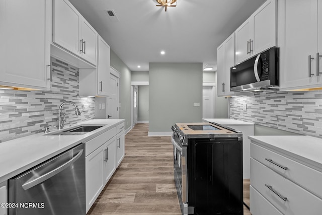 604 Willbrook Cir, Sneads Ferry, NC 28460 - kitchen with stainless steel appliances, a sink, light wood-style flooring, decorative backsplash, and light countertops