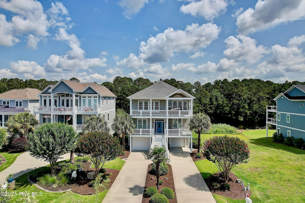 2820 Harborside Way, Southport, NC 28461 - raised beach house featuring a balcony, concrete driveway, a front yard, and an attached garage