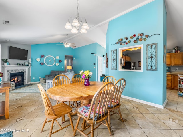 102 Sand Ct, Jacksonville, NC 28546 - dining space with light tile patterned flooring, vaulted ceiling, a ceiling fan, a tiled fireplace, and baseboards