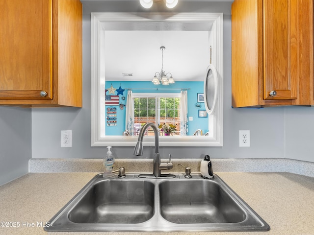 102 Sand Ct, Jacksonville, NC 28546 - kitchen featuring a sink, light countertops, a chandelier, and brown cabinets
