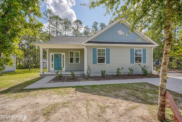 1858 E Boiling Spring Rd, Southport, NC 28461 - view of front of home featuring covered porch, board and batten siding, a front lawn, and a shingled roof