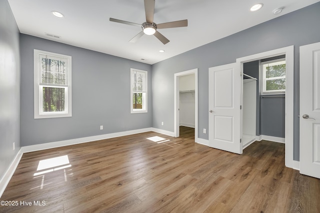1858 E Boiling Spring Rd, Southport, NC 28461 - unfurnished bedroom featuring multiple windows, a walk in closet, baseboards, wood finished floors, and recessed lighting