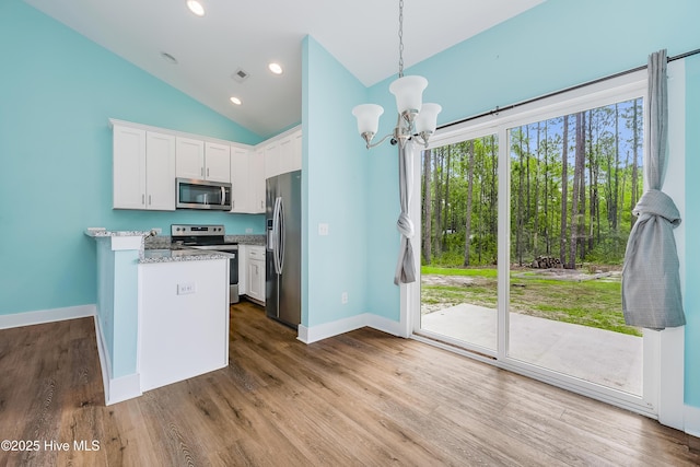 1858 E Boiling Spring Rd, Southport, NC 28461 - kitchen featuring stainless steel appliances, a chandelier, lofted ceiling, white cabinets, and baseboards