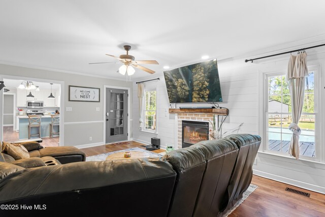 105 Teal Pointe Dr, Pikeville, NC 27863 - living area with plenty of natural light, a fireplace, wood finished floors, ceiling fan, and crown molding