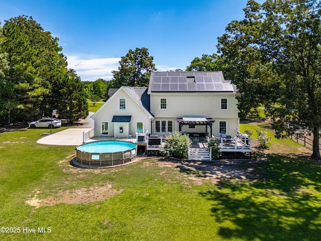 105 Teal Pointe Dr, Pikeville, NC 27863 - rear view of house featuring a wooden deck, an outdoor pool, roof mounted solar panels, a yard, and a pergola