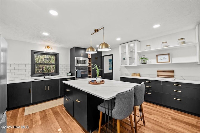 105 Tartan Trl, Southern Pines, NC 28387 - kitchen featuring stainless steel appliances, dark cabinetry, open shelves, a kitchen island, and light wood finished floors