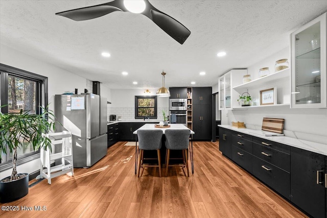 105 Tartan Trl, Southern Pines, NC 28387 - kitchen featuring stainless steel appliances, dark cabinetry, open shelves, light wood-type flooring, and a textured ceiling