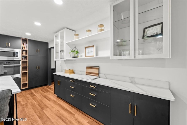 105 Tartan Trl, Southern Pines, NC 28387 - kitchen with open shelves, stainless steel appliances, dark cabinets, light wood-style flooring, and glass insert cabinets