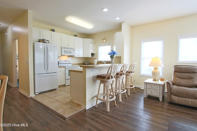 405 27th St Unit A, Sunset Beach, NC 28468 - kitchen featuring white appliances, a kitchen breakfast bar, open shelves, white cabinets, and dark wood finished floors