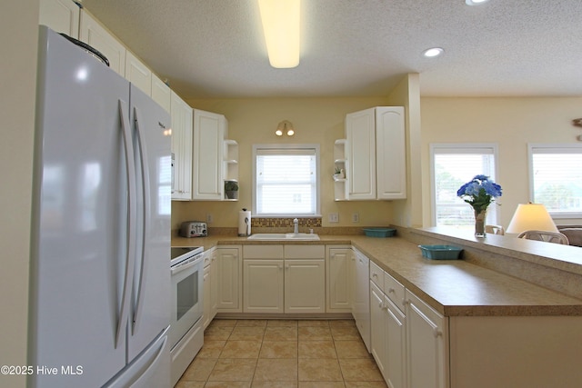 405 27th St Unit A, Sunset Beach, NC 28468 - kitchen with white appliances, open shelves, a sink, a peninsula, and plenty of natural light