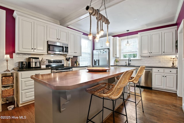 1305 Kenan St NW, Wilson, NC 27893 - kitchen with appliances with stainless steel finishes, wood counters, white cabinets, a kitchen island, and ornamental molding