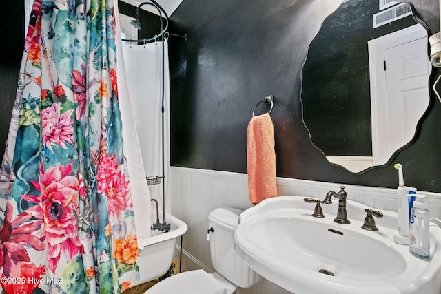 1305 Kenan St NW, Wilson, NC 27893 - bathroom featuring a sink, a wainscoted wall, toilet, and curtained shower