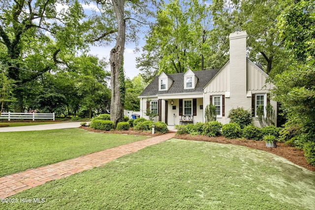 1305 Kenan St NW, Wilson, NC 27893 - view of front facade featuring a chimney, covered porch, board and batten siding, brick siding, and view of scattered trees