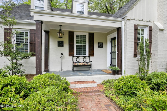 1305 Kenan St NW, Wilson, NC 27893 - view of exterior entry with brick siding, a porch, a shingled roof, and board and batten siding
