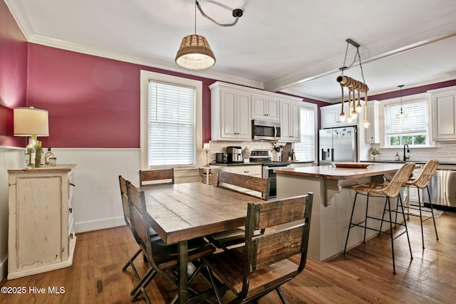 1305 Kenan St NW, Wilson, NC 27893 - kitchen with appliances with stainless steel finishes, ornamental molding, wood finished floors, wainscoting, and decorative backsplash