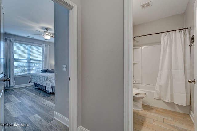 576 Steele Loop, Wilmington, NC 28411 - full bathroom with wood finished floors, shower / bath combo with shower curtain, toilet, baseboards, and ceiling fan