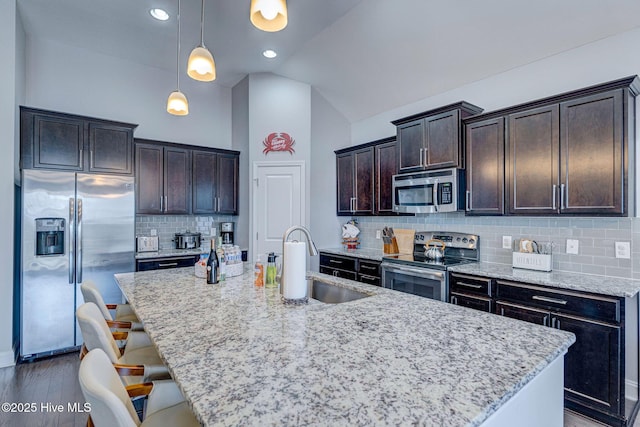 576 Steele Loop, Wilmington, NC 28411 - kitchen featuring appliances with stainless steel finishes, a sink, lofted ceiling, dark brown cabinets, and a center island with sink