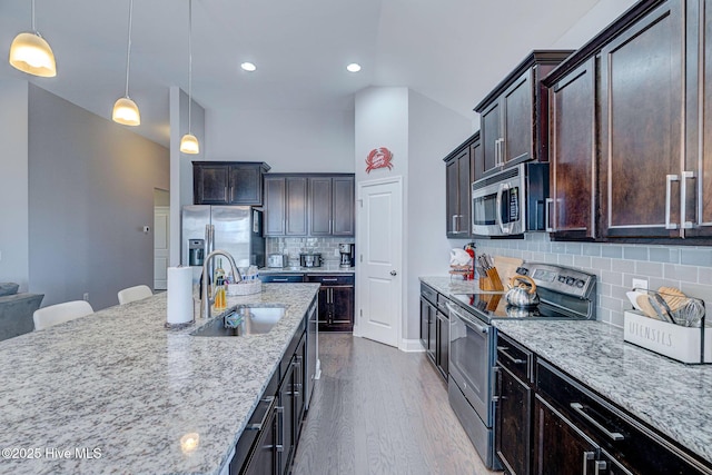 576 Steele Loop, Wilmington, NC 28411 - kitchen featuring appliances with stainless steel finishes, a sink, light stone counters, dark brown cabinetry, and recessed lighting